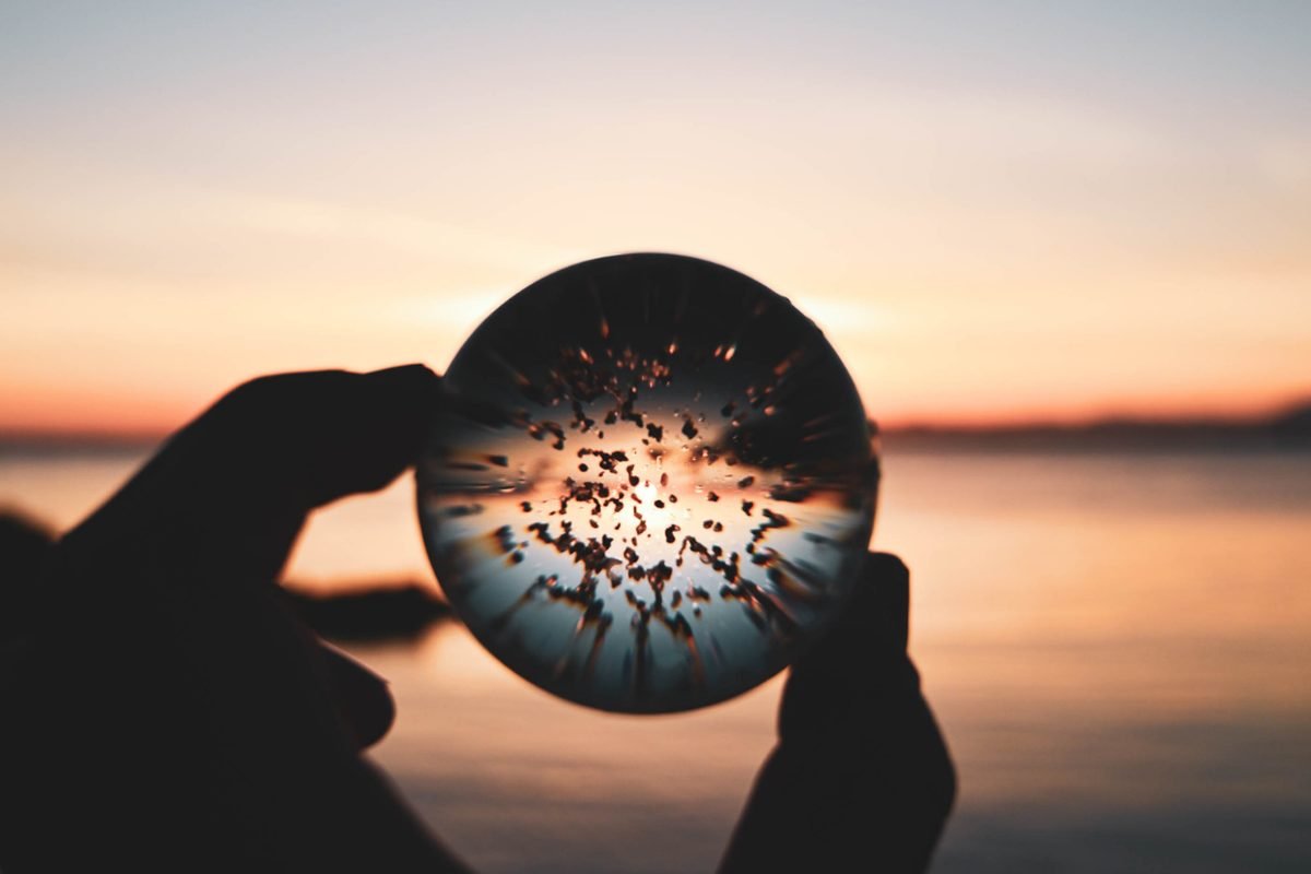 Hand holding a crystal ball at sunset